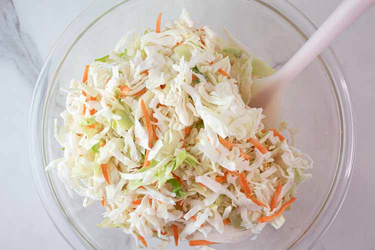overhead view of shredded cabbage and carrots added to the bowl to be mixed with the dressing