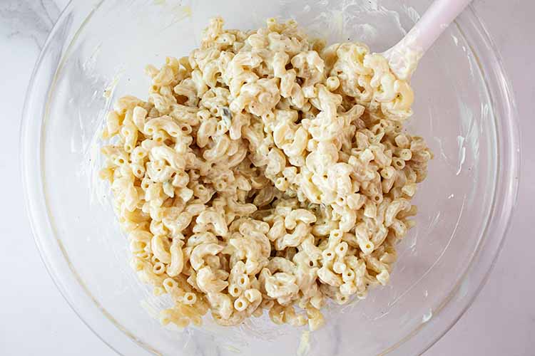 overhead view of macaroni added to the dressing ready to be combined