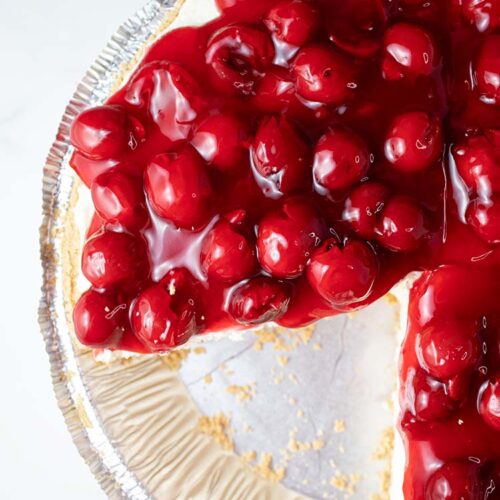overhead view of no bake cherry cheesecake ready to serve in a pie dish and one serving slice has been removed