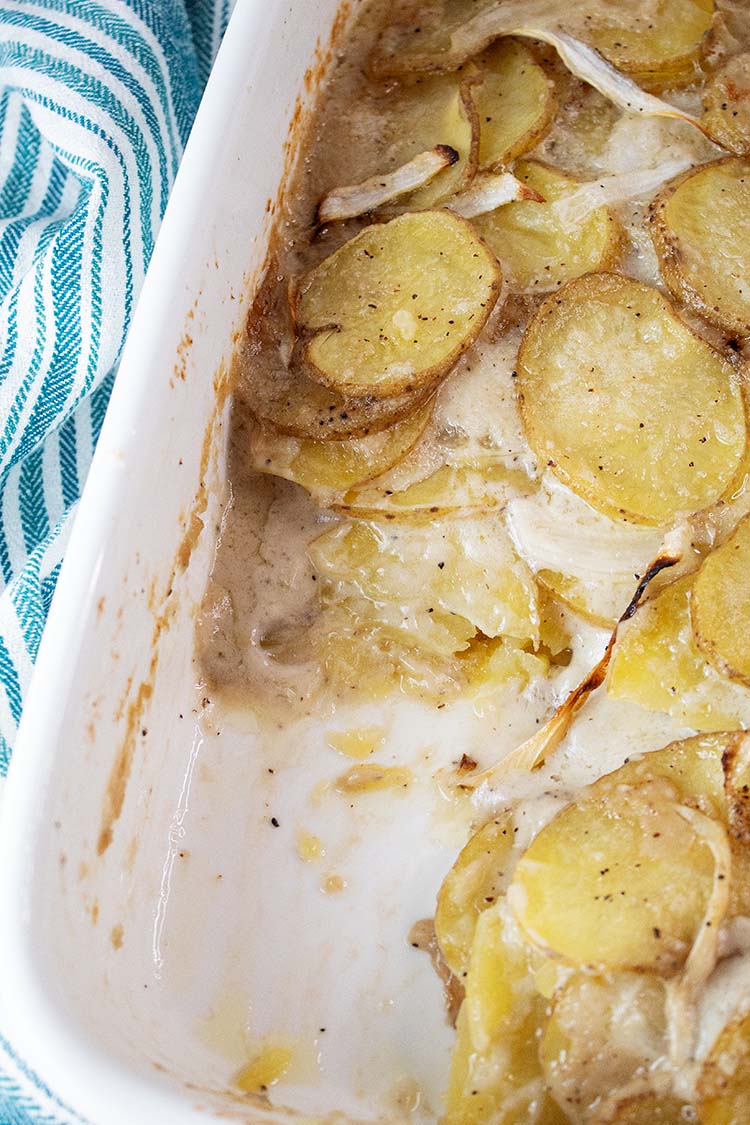 overhead view of casserole dish with scalloped potatoes and one serving removed