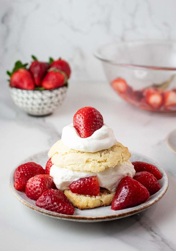 sideview of strawberry shortcake ready to serve with a small bowl of strawberries in the background