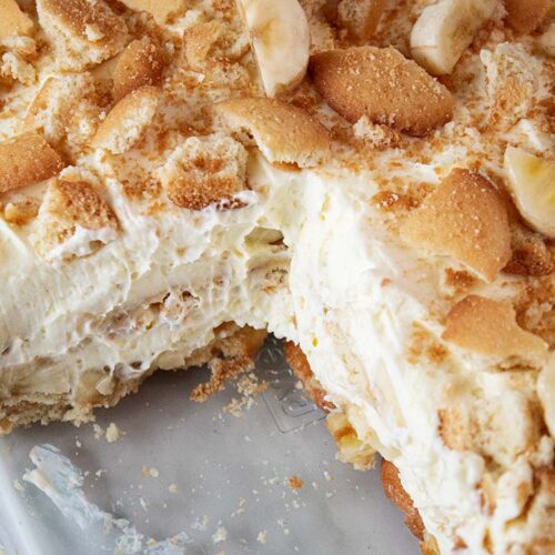 overhead view of banana pudding in a glass casserole dish with a portion size removed