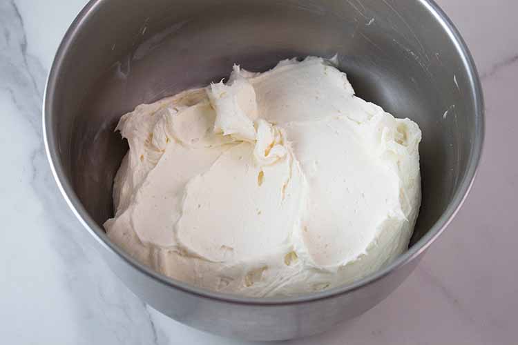 overhead view of steel mixing bowl with cream cheese and sweetened condensed milk thoroughly combined