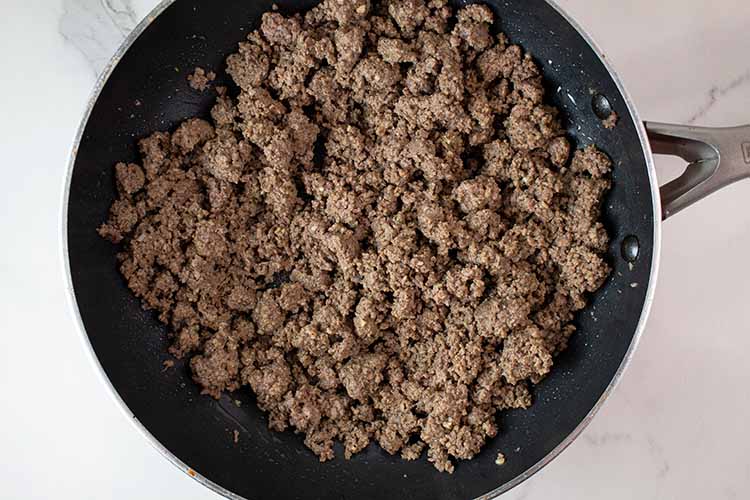 overhead view of ground beef cooked in a skillet and Big Mac seasoning added