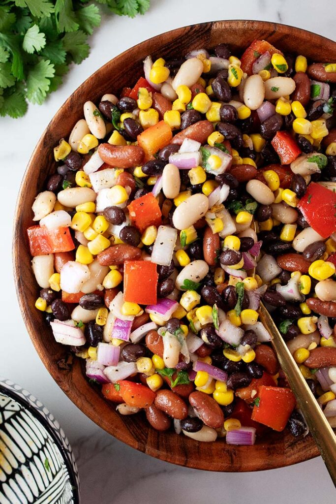 overhead view of Mexican bean salad in a large serving bowl with a serving spoon