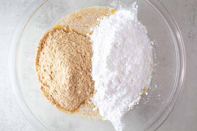 overhead view of sugar and crushed graham crackers added to the mixing bowl with peanut butter mixture