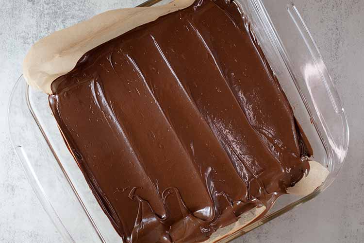 overhead view of melted chocolate poured over the peanut butter mixture in the casserole dish and ready to be chilled