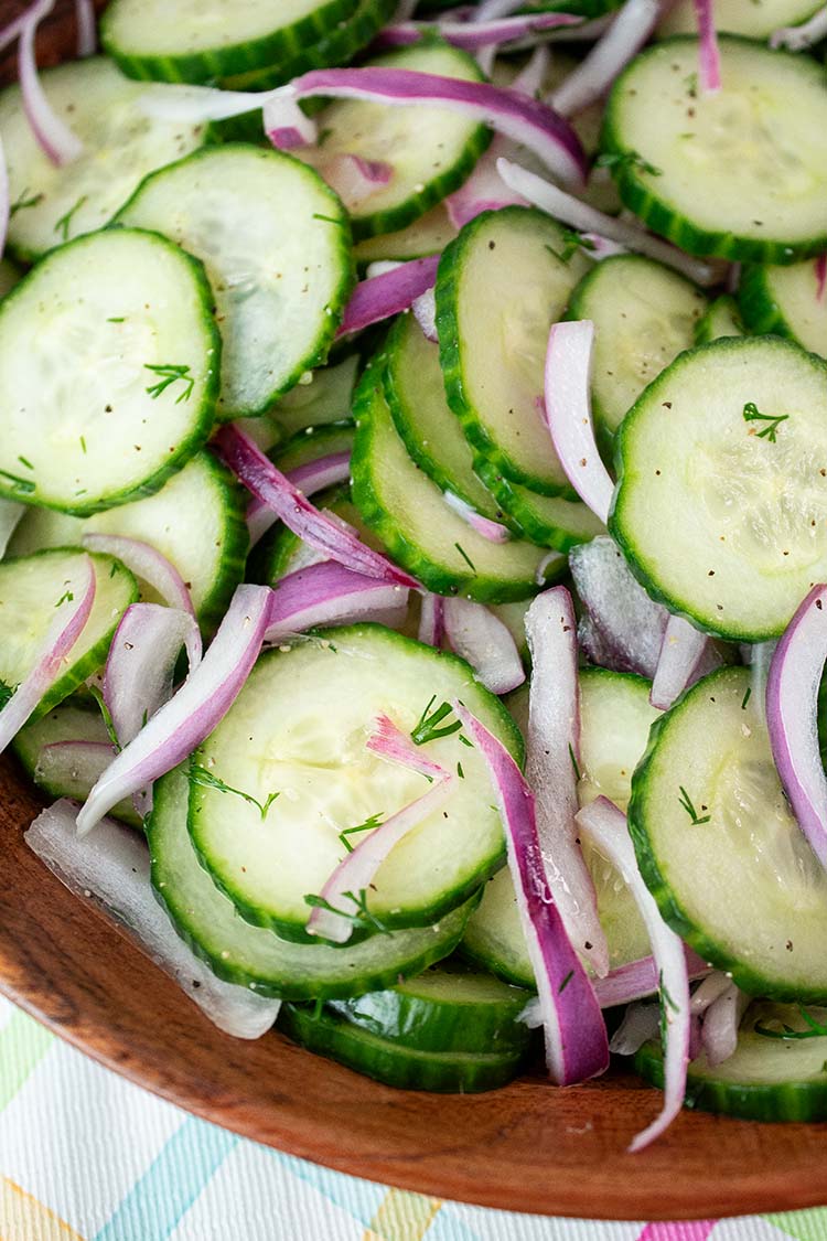 overhead view of cucumber salad and onions in a wooden serving bowl