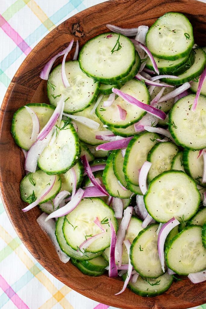 overhead view of cucumber salad with onions in a wooden serving bowl