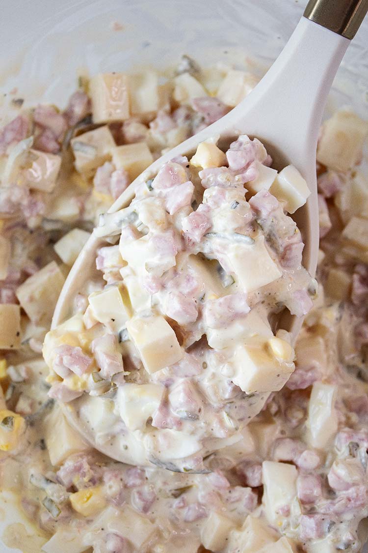 overhead view of ham salad ready to serve with one portion being removed with a serving spoon