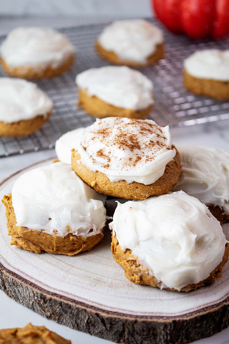 sideview of pumpkin cookies with cream cheese frosting ready to serve on a white dish