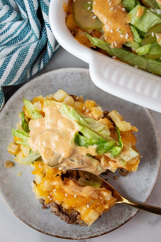 overhead view of a serving size of Big Mac casserole on a serving dish next to the casserole dish