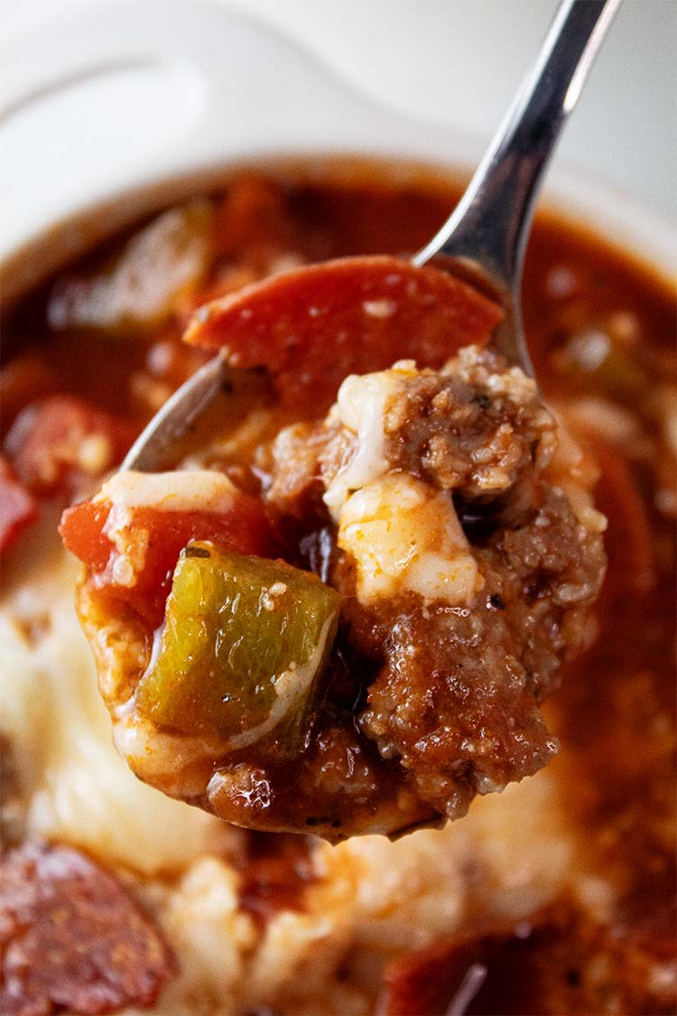 overhead view of pizza soup in a bowl with a small spoonful of it being removed