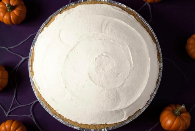 overhead view of no bake cheesecake ready to be topped with cherries and decorated with spooky Halloween decor