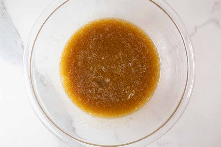overhead view of liquid ingredients mixed in glass mixing bowl