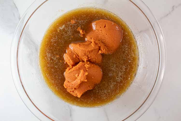 overhead view of pumpkin added to liquid ingredient mixture